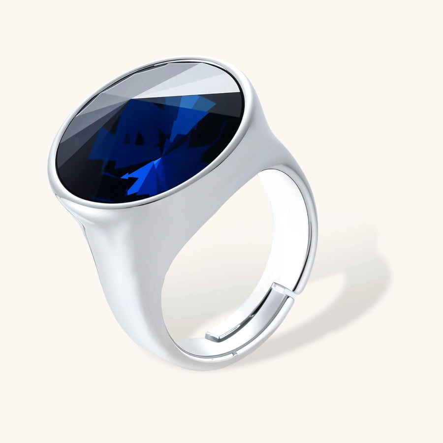 Large oval blue cubic zirconia ring in palladium-plated setting with adjustable band design on neutral background.
