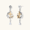 Two-tone star earrings with gold celestial motifs, silver chains, and clear crystal droplets on white background.