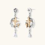 Two-tone star earrings with gold celestial motifs, silver chains, and clear crystal droplets on white background.