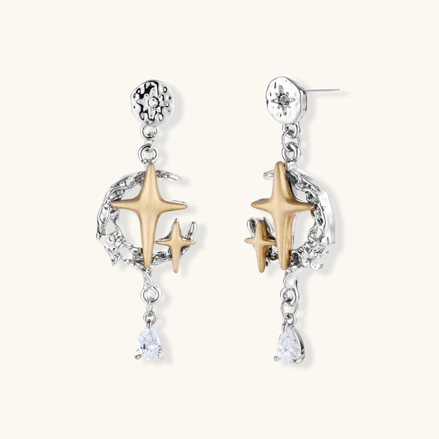 Two-tone star earrings with gold celestial motifs, silver chains, and clear crystal droplets on white background.