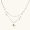 Two-layer silver-toned necklace with star charms and dagger pendant featuring golden sun motif on white background.
