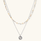 Two-layer necklace with natural stone chips and eco-brass beads, featuring a circular wrapped pendant on cream background.