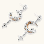 Detailed eco-brass dangle earrings featuring crescent moons with gold rope details and dangling star charms on white background.