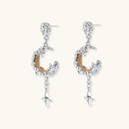 Detailed eco-brass dangle earrings featuring crescent moons with gold rope details and dangling star charms on white background.