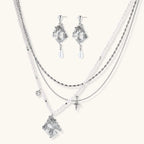 Ornate silver-toned masquerade mask jewelry set featuring rhinestone details and pearl drop earrings on white background.