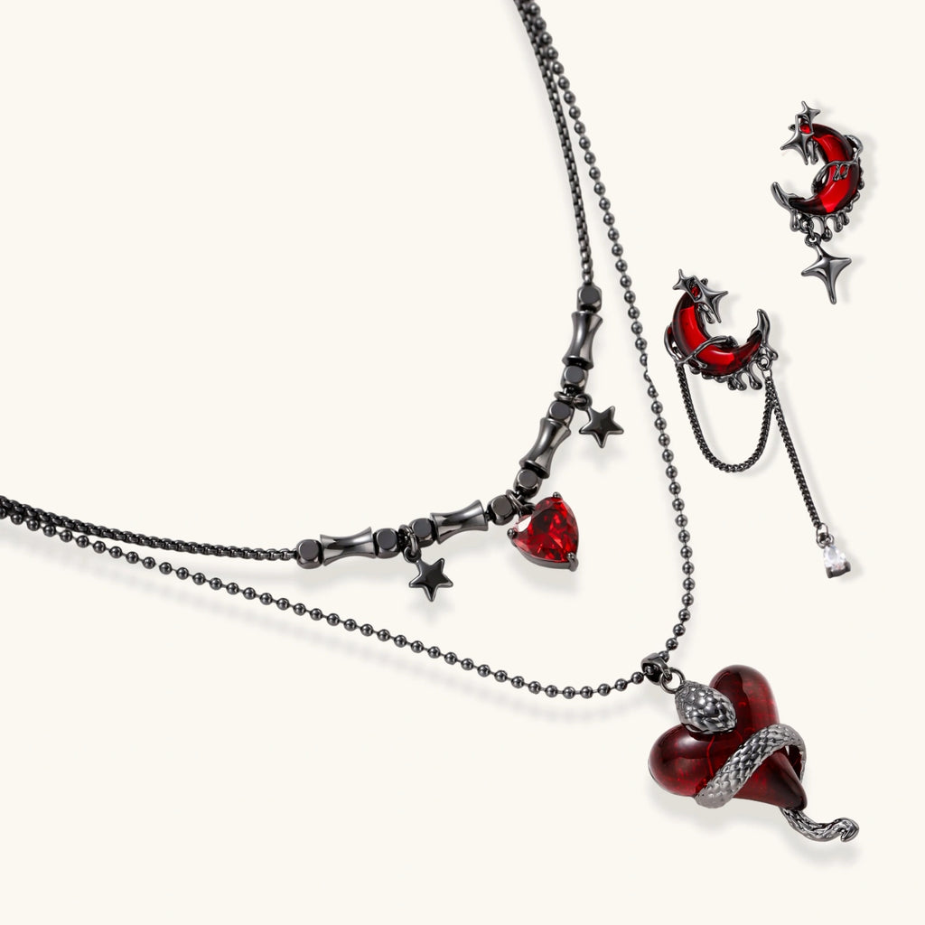 Gothic jewelry set with asymmetrical black metal earrings featuring red crescent moons, stars, and layered necklaces with heart pendants