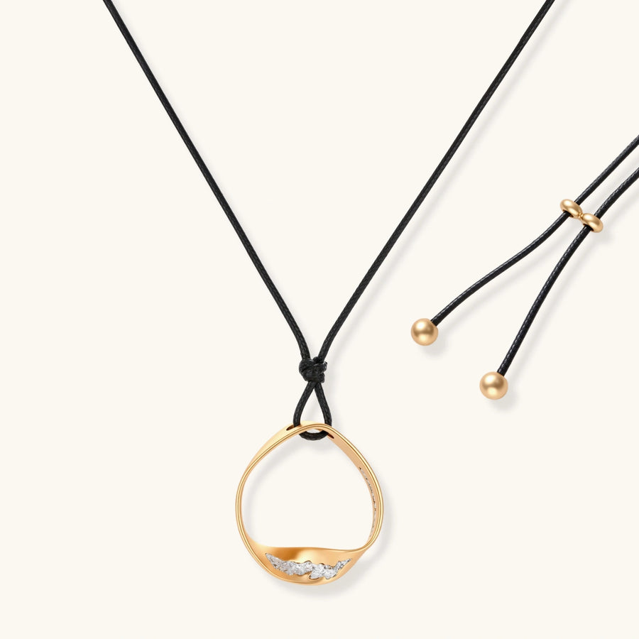 Geometric circle pendant necklace with crystal cluster on adjustable black cord, available in gold and silver finishes.