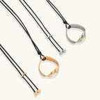 Adjustable black cord necklace with circular gold pendant featuring sparkly crystal accents on white background.