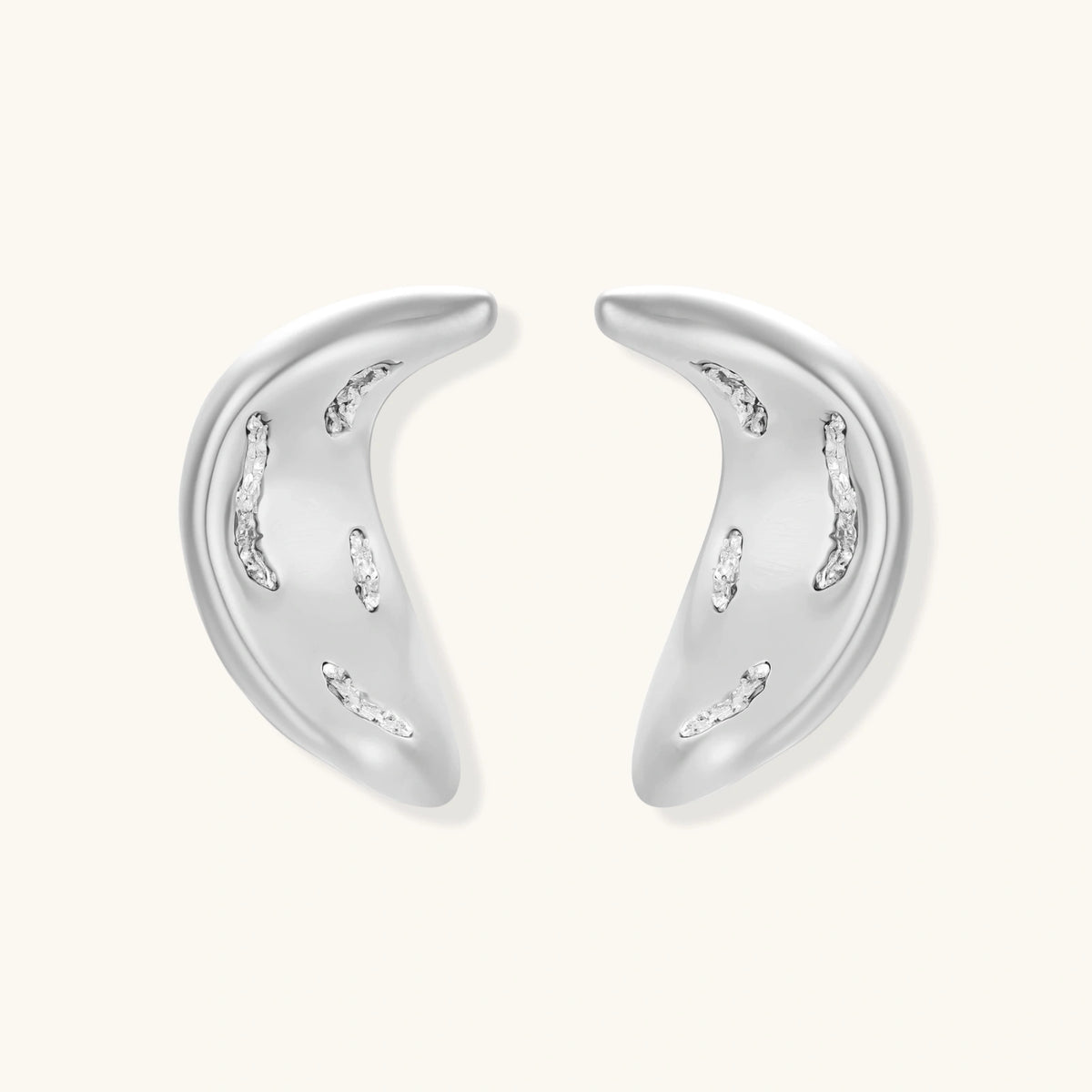 Crescent moon shaped pendant and earrings in eco-zinc alloy with curved crystal inlay patterns on light background.