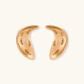 Pair of gold crescent moon-shaped stud earrings with textured surface details on cream background.