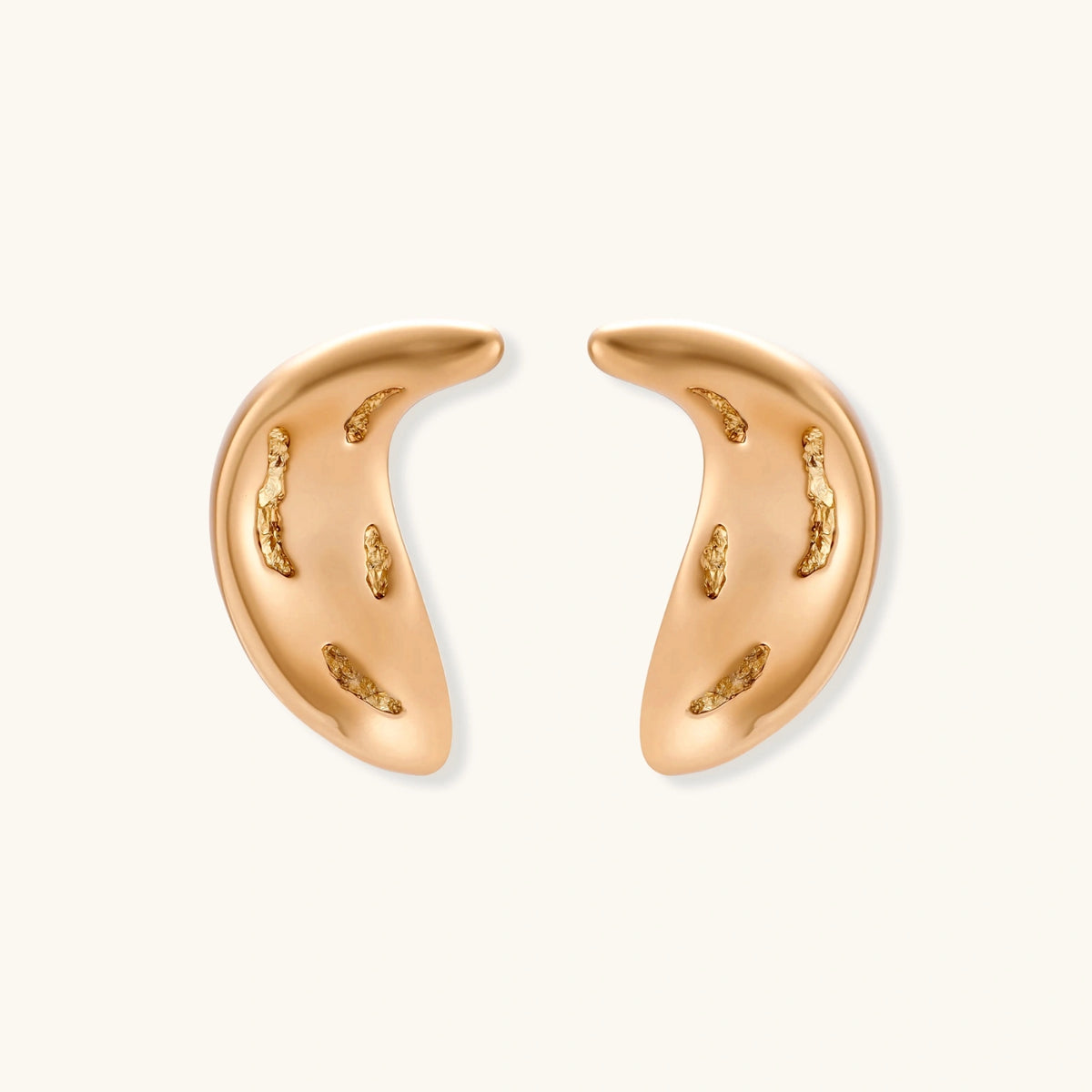 Pair of gold crescent moon-shaped stud earrings with textured surface details on cream background.