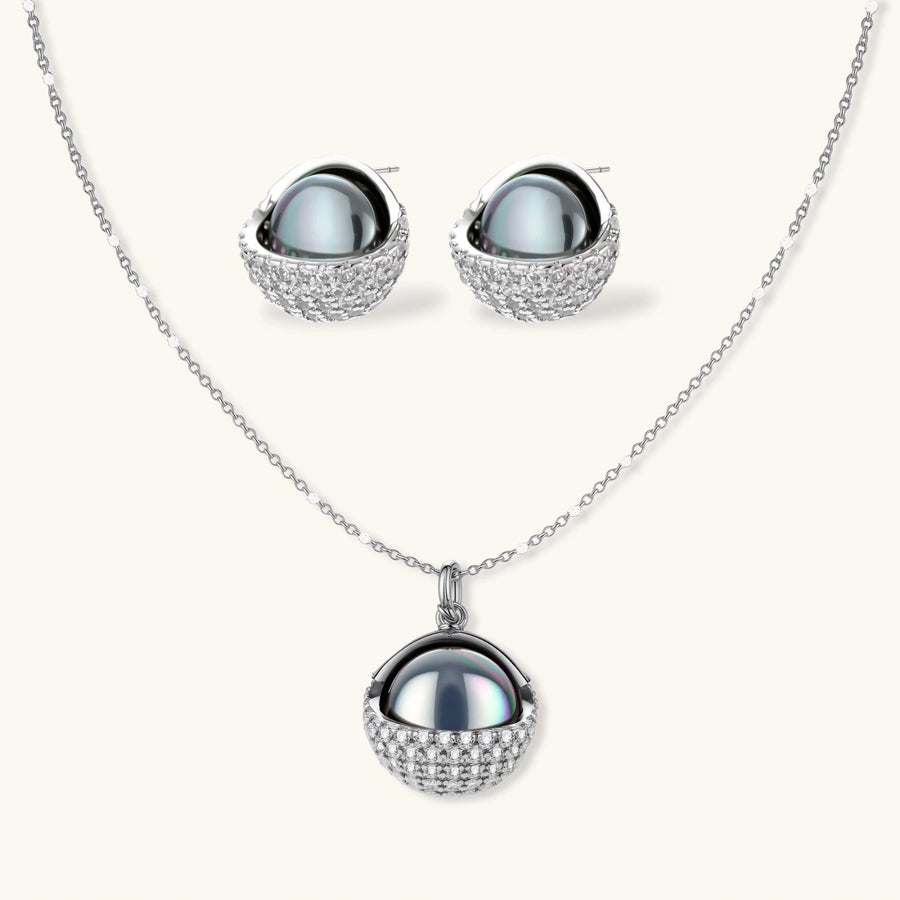 Silver gray Tahitian-style pearl pendant necklace and matching pave zirconia stud earrings set on cream background.