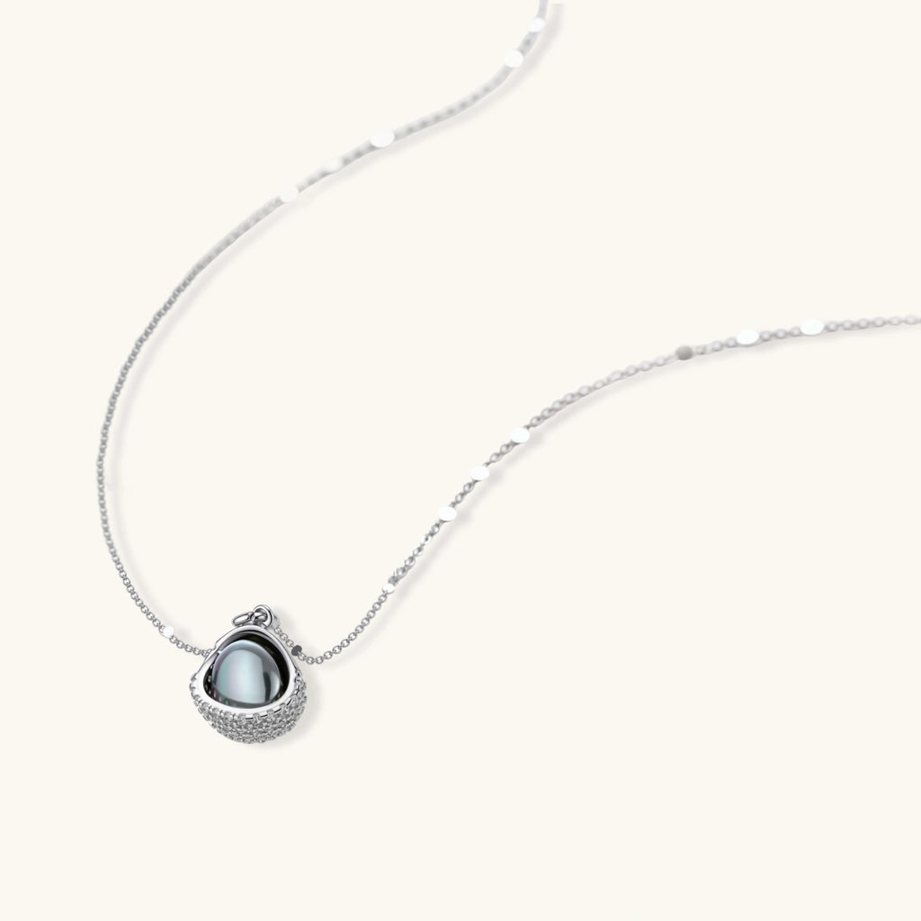 Silver gray Tahitian-style pearl pendant necklace and matching pave zirconia stud earrings set on cream background.