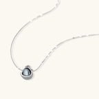 Silver gray Tahitian-style pearl pendant necklace and matching pave zirconia stud earrings set on cream background.
