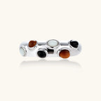 Adjustable platinum-plated ring with multiple oval cabochon stones in black, amber, and white tones on neutral background.